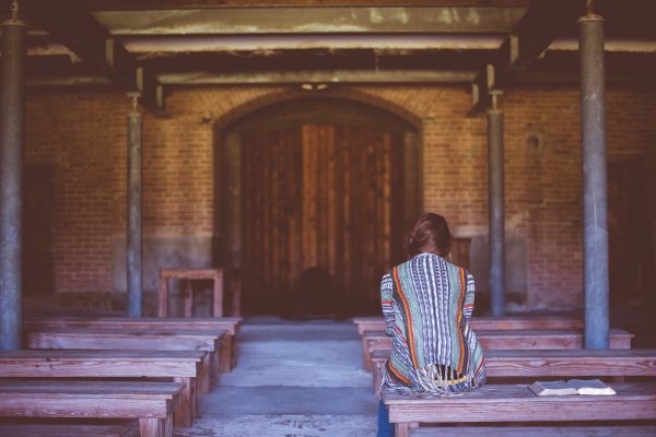 Woman sitting alone in rustic church