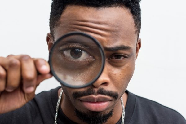 Black man playing with a magnifying glass