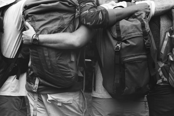 Group of friends hugging with backpacks