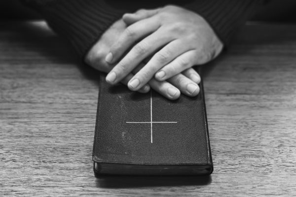 Hands over Bible on wooden table
