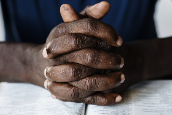 Black male hands resting on an open Bible
