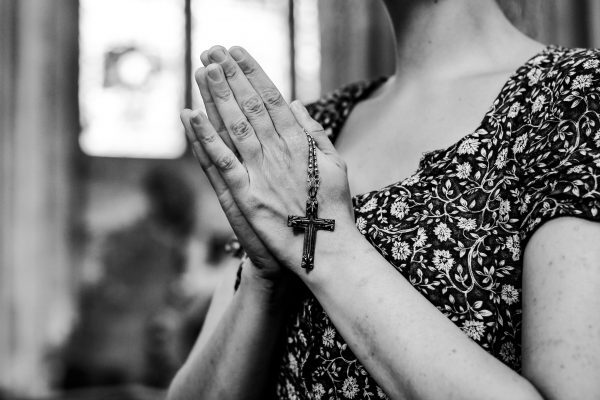 Catholic woman praying with a rosary at the church