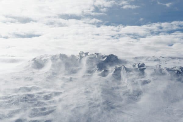 A snow covered mountain under a cloudy blue sky