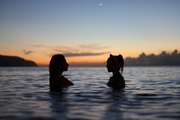 Two women looking at each other in water near Haleiwa, Oahu