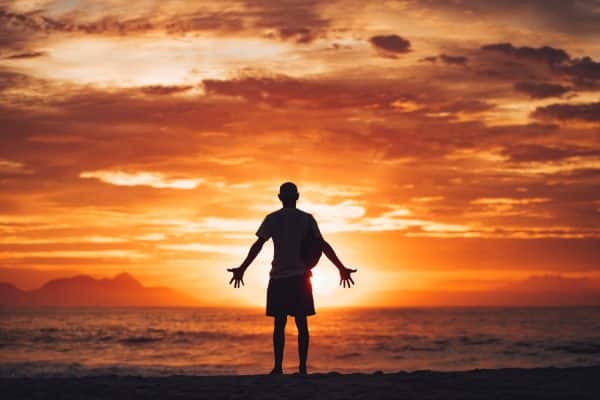 Man praying on the beach at sunrise