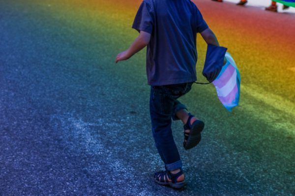 A child runs underneath the rainbow flag in Portland, Maine during the Pride Parade