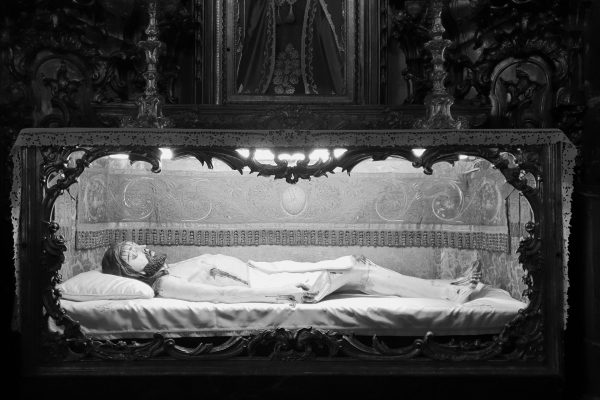 Black and White Photo of Statue of Jesus Laying in Glass Coffin