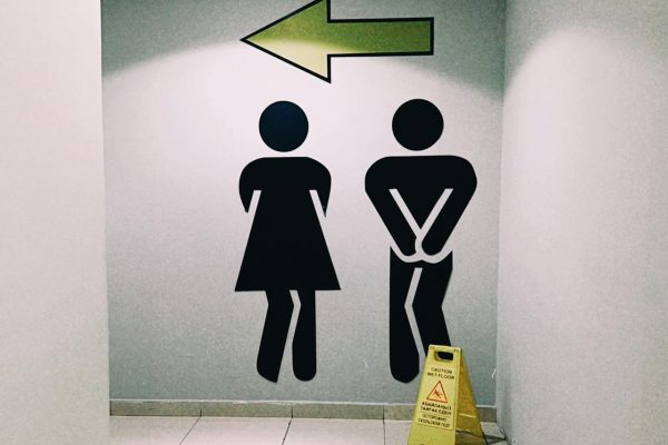 Modern restroom direction signage inside a mall with wet floor caution sign