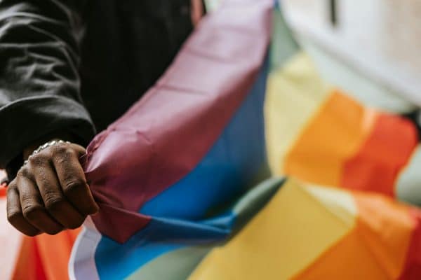 Black person holding rainbow flag