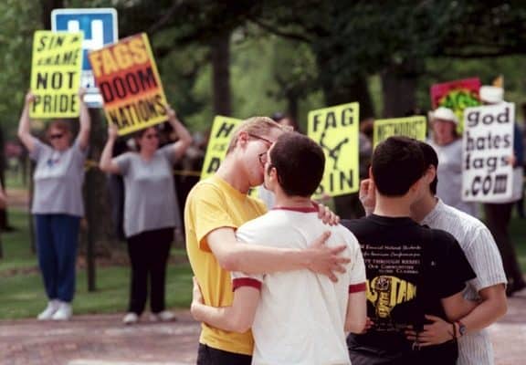 Gay and lesbian students kiss in front of a group of anti-homosexual protestors.